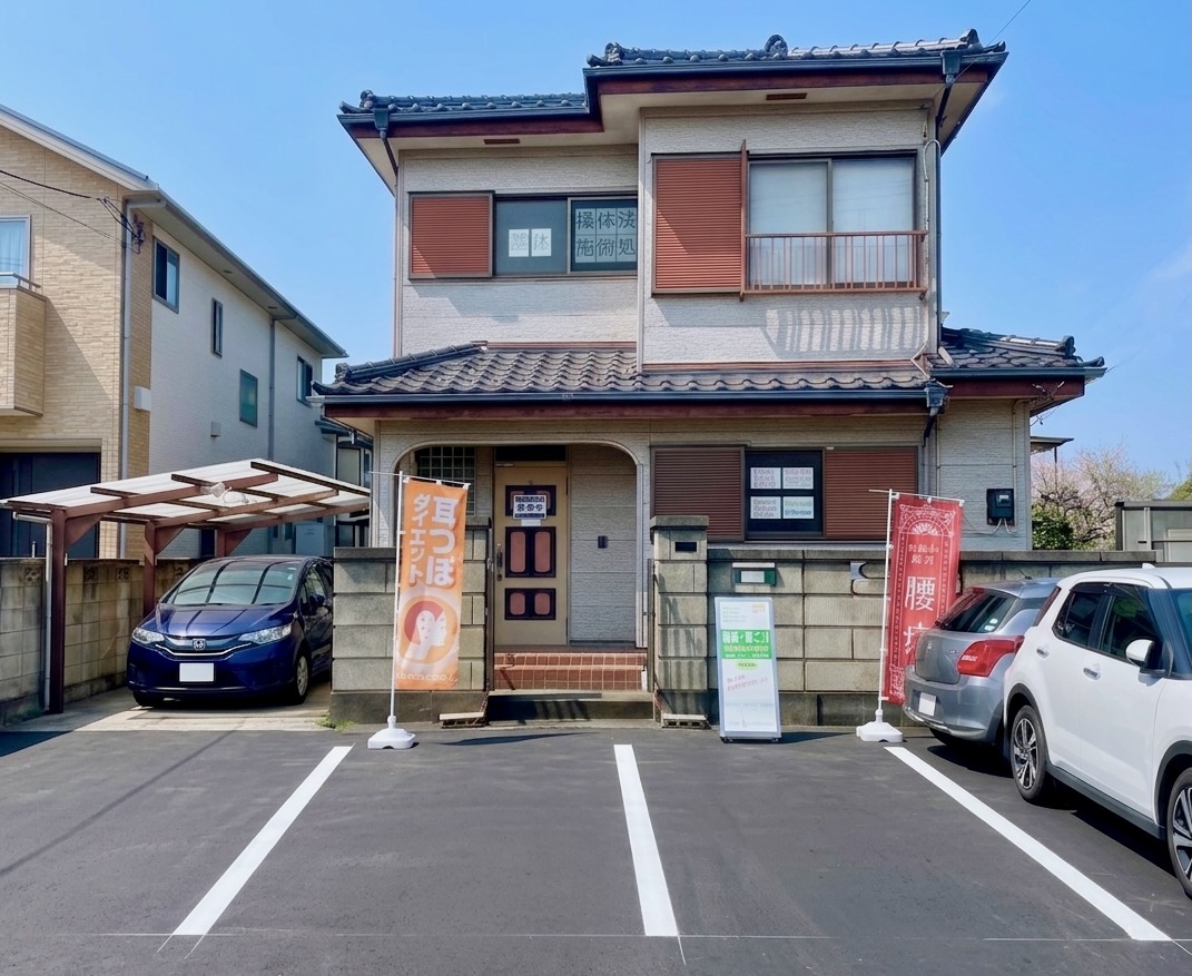 おき楽・ごく楽の外観。腰痛と耳つぼダイエットの幟旗が目印の昭和レトロな一軒家です。